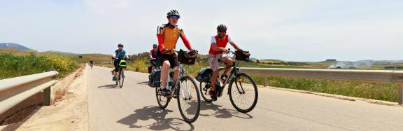 Group of cyclists riding along a rural road, enjoying cycling south Italy through open landscapes